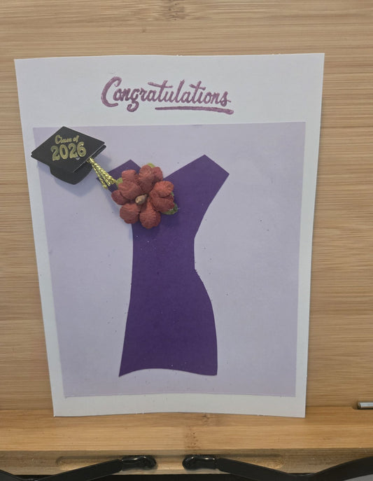 Graduation-themed card with a purple silhouette of a dress, accented with a flower and cap and tassel.